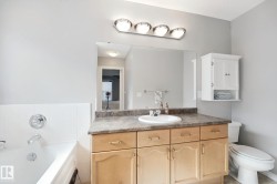 Full vanity with an integrated sink, surface-mount lighting, wall-mounted storage cabinet, and a built-in tub with tile surround - 