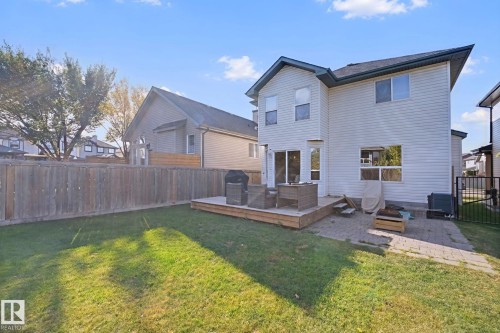 Expansive lawn area, private wood fence, ground-level wood deck, paver patio, and sliding glass door access - 324 Ascott Crescent, Sherwood Park, AB 