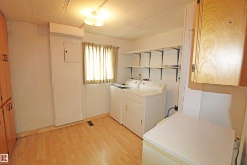 Laundry area featuring wood-finish flooring, built-in shelving, and light wood cabinetry - #16 4202 45 St, Wetaskiwin, AB 