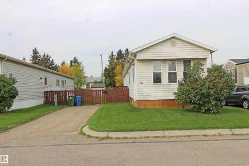 Single-story residence featuring light-colored siding, a pitched roofline, and a manicured front lawn - #16 4202 45 St, Wetaskiwin, AB 