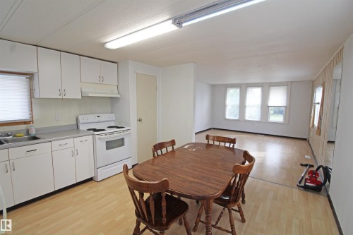 White cabinetry, stainless steel sink, white electric range, wood-finish flooring, multiple windows - #16 4202 45 St, Wetaskiwin, AB 