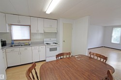 Kitchen featuring white cabinetry, a double basin sink, white electric range, and wood-finish flooring throughout - 