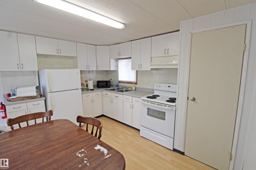 Kitchen with white cabinetry, light-toned wood-finish flooring, and white appliances - #16 4202 45 St, Wetaskiwin, AB 