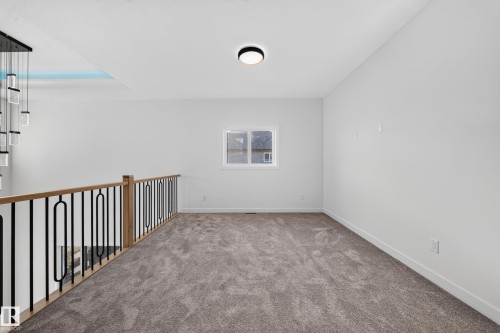 Loft area featuring grey carpeting, white walls, a single window, and a modern light fixture - 13024 186 Avene Nw, Edmonton, AB 