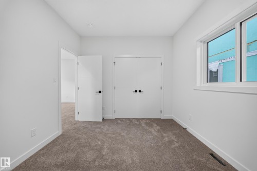 Neutral tone carpeted flooring, white walls, double-door closet with dark hardware, and a window with white trim - 13024 186 Avene Nw, Edmonton, AB 