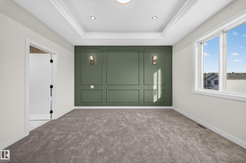 Tray ceiling with recessed lighting, decorative wall paneling, wall sconces, plush carpet flooring, and a large window - 13024 186 Avene Nw, Edmonton, AB 