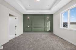 Tray ceiling with recessed lighting, decorative wall paneling, wall sconces, plush carpet flooring, and a large window - 