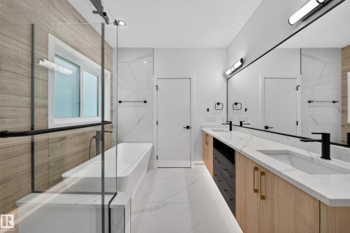 Freestanding soaking tub with a glass shower enclosure, dual vanity with undermount sinks, and wall-mounted lighting fixtures - 13024 186 Avene Nw, Edmonton, AB 