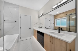 Freestanding tub with a glass shower enclosure, dual vanity with undermount sinks, and a full-width mirror - 