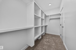 Custom built-in white shelving, integrated hanging rods, recessed ceiling lighting, and carpeted flooring - 
