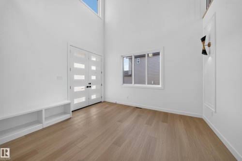 Double entry doors with frosted glass panels, wood-finish flooring, built-in storage bench, and an upper transom window - 13024 186 Avene Nw, Edmonton, AB 