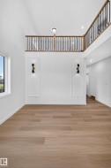 Wood-finish flooring, high ceilings, and a second-level open railing with black spindles - 