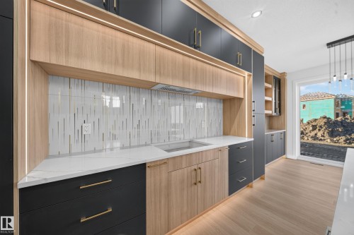 Integrated lighting, wood-finish flooring, white countertops, built-in cabinetry, and a full-light exterior door - 13024 186 Avene Nw, Edmonton, AB 