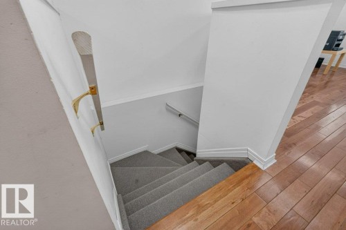 Carpeted staircase with a wood handrail and brass-finish brackets - Edmonton, AB 