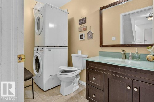Bathroom featuring a dark wood-finish vanity, glass countertop with integrated sink, brushed nickel faucet, and a wall-mounted mirror - Edmonton, AB 