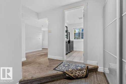 Recessed lighting illuminates the hallway with carpeting, leading to a space with tile flooring, a window, and built-in cabinetry - Edmonton, AB 