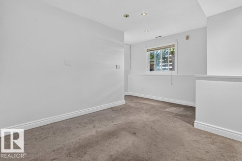 Bright corner room with neutral white walls, recessed ceiling lighting, and warm wood-finish flooring - Edmonton, AB 