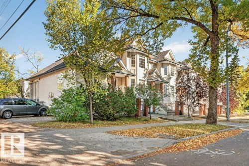 Classic Colonial architecture with brick and stone exterior accents, complemented by mature shade trees and established landscaping - Edmonton, AB 