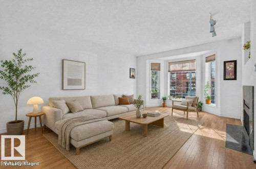 Hardwood flooring, bay windows with natural light, a fireplace with a stone hearth, and white wall finishes - Edmonton, AB 
