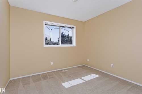 Neutral tone wall paint, light-colored carpeting, white trim, and a window with architectural grilles - 4112 37A Avenue Nw, Edmonton, AB 