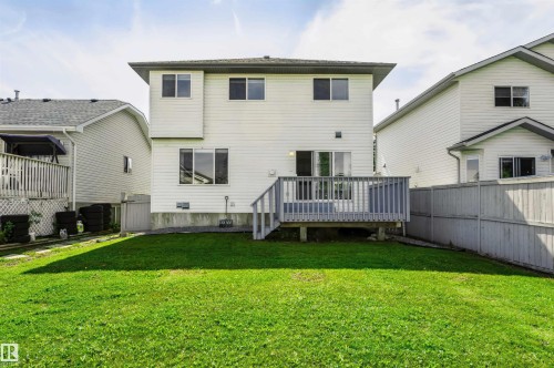 Expansive rear lawn, two-story exterior with white siding, rear deck with wood railing, sliding glass patio doors, and a wood privacy fence - 4112 37A Avenue Nw, Edmonton, AB 
