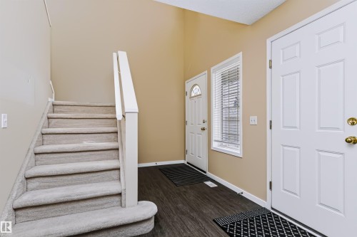 Entryway featuring wood-finish flooring, a white paneled door with brass hardware, and a window with blinds - 4112 37A Avenue Nw, Edmonton, AB 