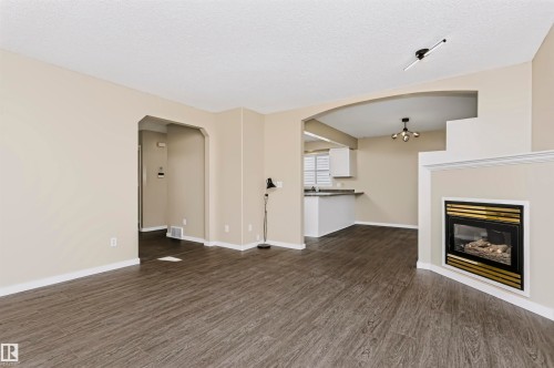 Wood-finish flooring throughout, fireplace with a brass-trimmed insert, arched doorway, and track lighting - 4112 37A Avenue Nw, Edmonton, AB 