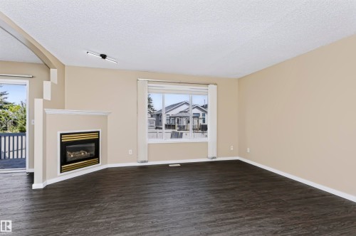 Living space with wood-finish flooring, a built-in fireplace, and a large window - 4112 37A Avenue Nw, Edmonton, AB 