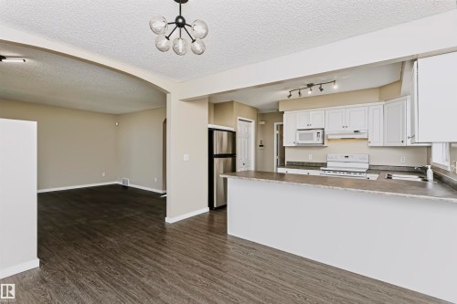 Kitchen featuring white cabinetry, stainless steel appliances, and a breakfast bar - 4112 37A Avenue Nw, Edmonton, AB 