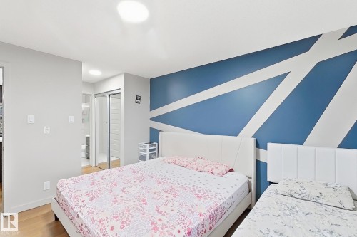 Wood-finish flooring, recessed lighting, and a blue accent wall with white geometric patterns - #116 4008 Savaryn Dr Sw Sw, Edmonton, AB 