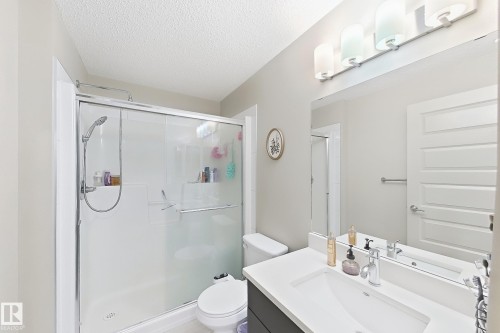 White vanity with an integrated rectangular sink, chrome faucet, and expansive mirror - #116 4008 Savaryn Dr Sw Sw, Edmonton, AB 