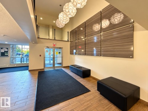 Two-story entry with wood-finish flooring, glass railing, and decorative wall panels - #116 4008 Savaryn Dr Sw Sw, Edmonton, AB 