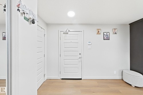 Light wood-finish flooring, white paneled doors, and a recessed ceiling light - #116 4008 Savaryn Dr Sw Sw, Edmonton, AB 