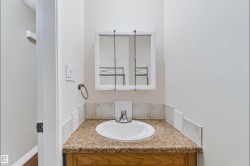 Vanity with an integrated sink, granite-look countertop, tile backsplash, and wood-finish cabinetry - 