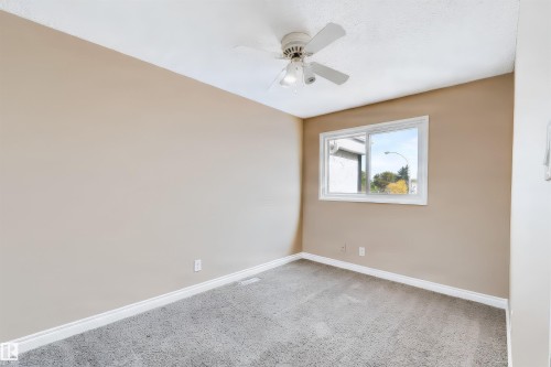 Neutral-toned walls, carpet flooring, a window with white trim, and a ceiling fan with integrated lighting - 155 Primrose Gardens Gardens Nw, Edmonton, AB 