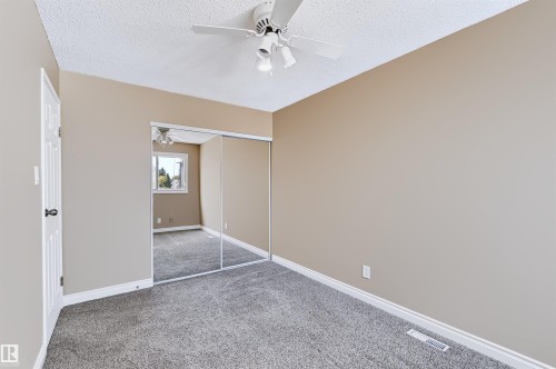 Wall-to-wall carpeting, mirrored sliding closet doors, ceiling fan with integrated lighting, and a white paneled door - 155 Primrose Gardens Gardens Nw, Edmonton, AB 