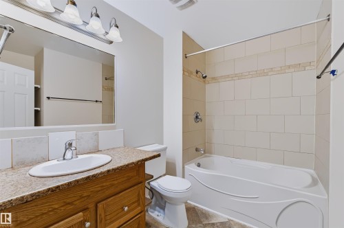 Vanity with a granite-style countertop, undermount sink, and wood-finish cabinetry - 155 Primrose Gardens Gardens Nw, Edmonton, AB 