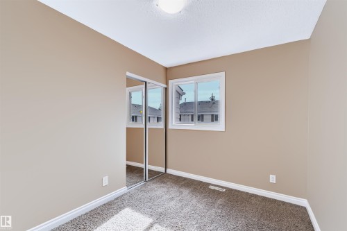 Carpeted flooring, neutral wall tones, white trim, sliding mirrored closet doors, and white frame window - 155 Primrose Gardens Gardens Nw, Edmonton, AB 