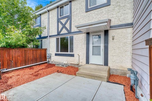 Stucco exterior with decorative trim, concrete steps, and a white entry door with an awning - 155 Primrose Gardens Gardens Nw, Edmonton, AB 