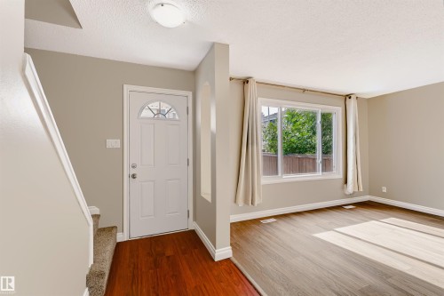 Entryway featuring a white paneled door with decorative glass, wood-finish flooring, and a flush mount ceiling light - 155 Primrose Gardens Gardens Nw, Edmonton, AB 