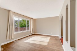Expansive room featuring wood-finish flooring, broad windows, arched doorways, and a neutral color palette - 