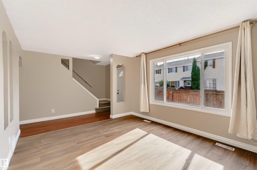 Spacious room with wood-finish flooring, neutral paint, and white trim - 155 Primrose Gardens Gardens Nw, Edmonton, AB 