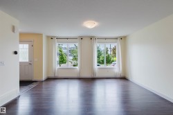 Spacious room featuring rich wood-finish flooring, bright white walls, and a recessed ceiling light - 