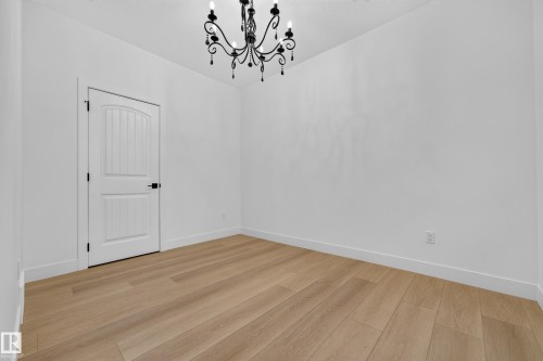 Light wood-finish flooring, white walls, and a black wrought-iron chandelier - 11010 174A Avenue Nw, Edmonton, AB 
