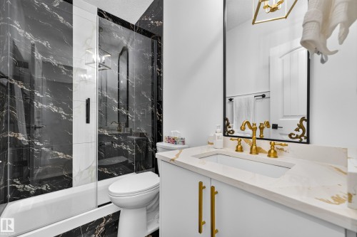 White vanity with gold-finish hardware, a white undermount sink, and a white countertop with gold veining - 11010 174A Avenue Nw, Edmonton, AB 