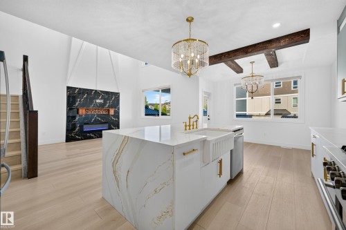 White kitchen island with a waterfall edge, integrated farmhouse sink, and brass-finish faucet - 11010 174A Avenue Nw, Edmonton, AB 