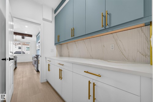 White lower cabinetry with gold-finish hardware, light blue upper cabinetry, and a white countertop - 11010 174A Avenue Nw, Edmonton, AB 