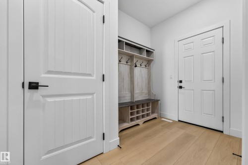 Light wood-finish flooring, built-in storage bench with shelving, white panel doors, and matte black hardware - 11010 174A Avenue Nw, Edmonton, AB 