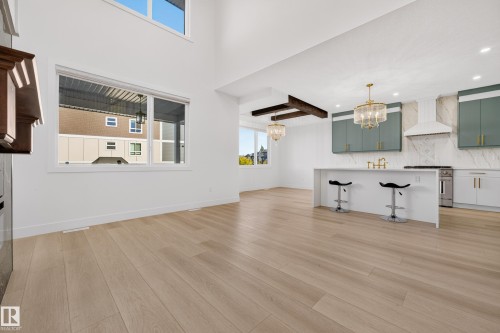 Open-concept living space featuring wood-finish flooring, high ceilings, large windows, recessed lighting, and a kitchen with an island, stone countertops, and a tile backsplash - 11010 174A Avenue Nw, Edmonton, AB 