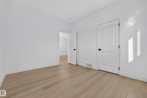 Wood-finish flooring, white walls, and a white interior door with black hardware - 11010 174A Avenue Nw, Edmonton, AB 